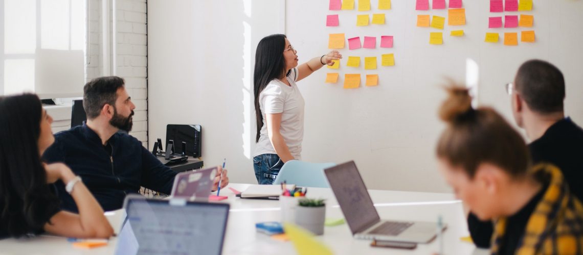 adult class course with teacher placing sticky note on board